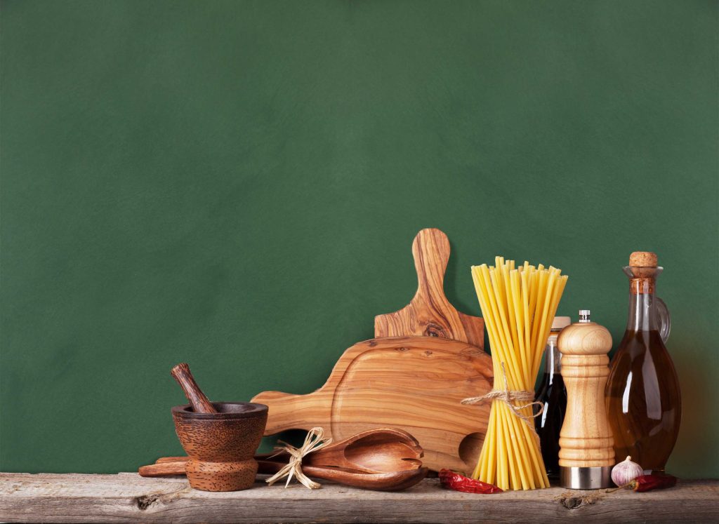 Kitchen utensils, herbs and spices on shelf against rustic wooden wall
